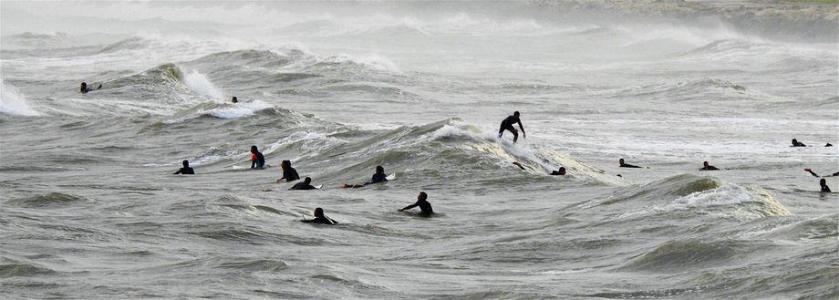 Surfers in the grey winter waters of Tel Aviv.