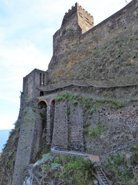 The stone staircase leading to the entrance of the castle (covered with a protective net), and bellow the stairs that take the visitor down to the base of the castle rock.