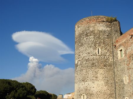 The big north-western tower of Ursino and smoke coming from Etna in the background.