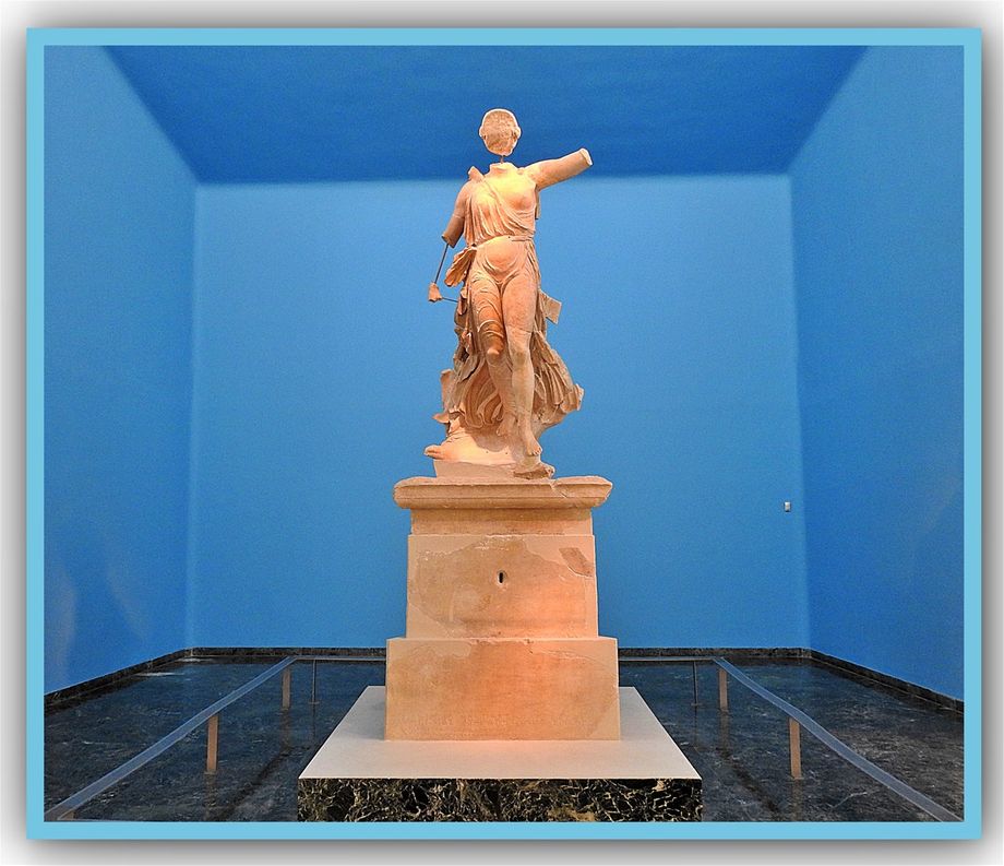 The Nike of Paionios is a statue of the Greek goddess of victory, Nike, made by sculptor Paionios in 425–420 BC. Made of Parian marble, the statue was restored from many fragments, but is lacking face, neck, forearms, part of left leg, toes and some fragments of drapery. It also had wings. The goddess is shown landing gently on her left foot, with the drapery blown against her body. The statue was excavated at Olympia in 1875–76 and originally stood near the temple of Zeus on a triangular 6-metre high pillar.