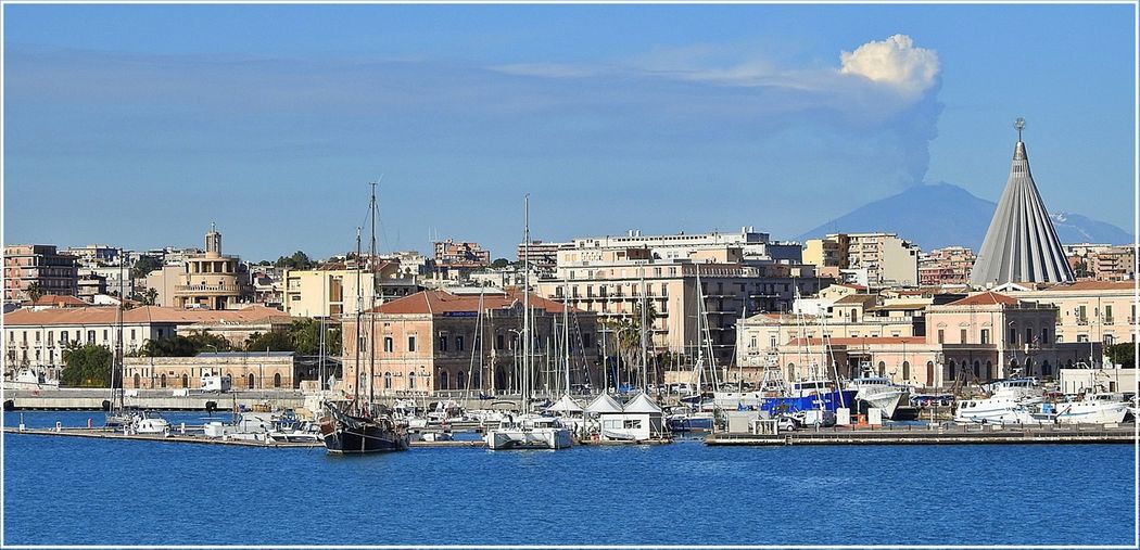 Central Syracuse seen from Ortygia island. Mount Etna can be seen at the background smoking.