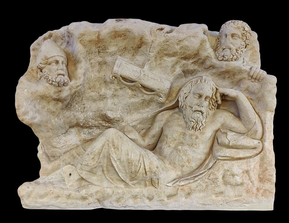 Marble slab found in Merenda. Before the middle of the 2nd century A.D.  The slab depicts the myth of the stealing of the weapons owned by the homeric hero Philoctetes, who had resorted to Lemnos, according to the version of the tragic poet Euripides.  Philoctetes, rather old and ill, is represented in a bent position into a cave. At the background, behind the cave's entrance, two male heads are visible. The first one, with a thick beard and a conical pilos is identified with Odysseus. The other one, probably Diomedes, with thick hair styled in locks and a beard dispossesses Philoctetes of his bow and quiver.