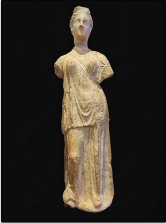 Marble statuette of Artemis.  End of 4th century B.C.  She is wearing a chiton with short sleeves and a peplos with a long ungirded 'apoptygma' (overfold). The telamon of her pharetra is placed obliquely on her chest. Her hair is elaborately tied at the upper part of her head.
